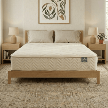 Bedroom with a wooden bed frame and Mattress Makers mattress, flanked by two nightstands with lamps.