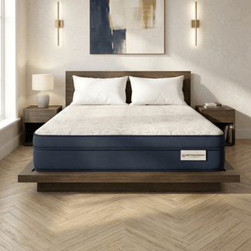 Navy blue and white Mattress Makers mattress on a wooden bed frame in a bedroom setting.