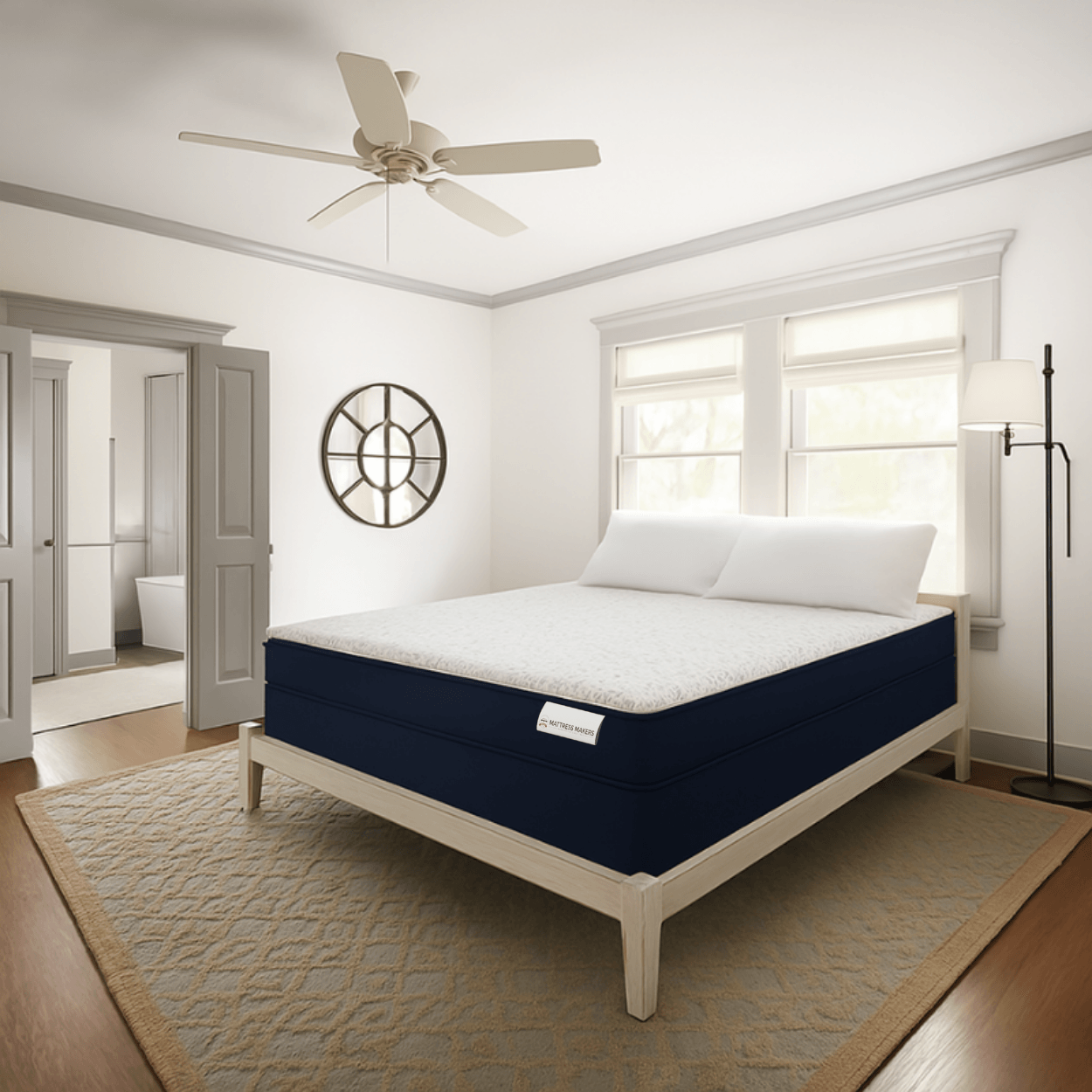 Navy blue and white Mattress Makers mattress in a bedroom setting with windows and a ceiling fan.