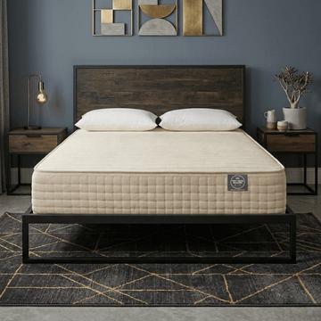 Beige Mattress Makers mattress on a wooden bed frame in a modern bedroom with abstract art on the wall.