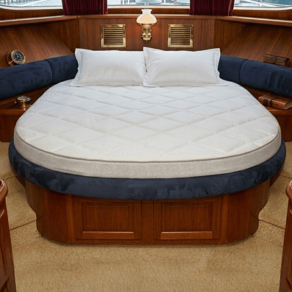 Circular bed with white Mattress Makers mattress and blue trim in a boat interior setting